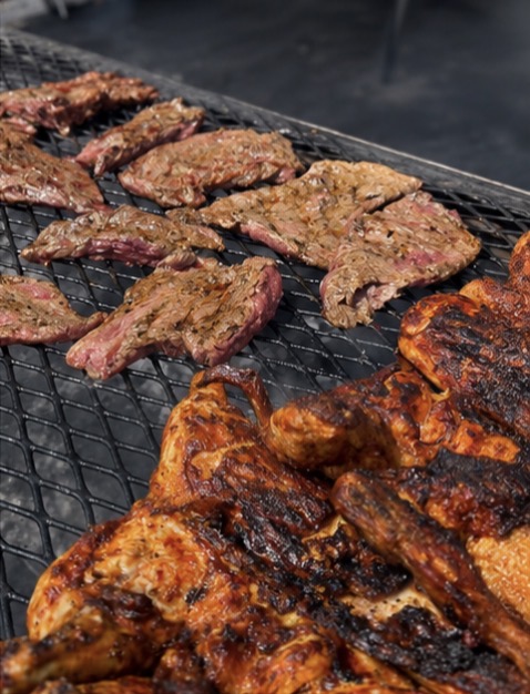 Skirt steak searing on the grill next to grilled chicken
