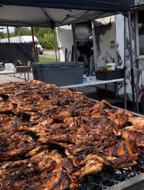 Rows of charcoal-grilled whole chickens on the food truck grill